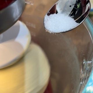 Un cucchiaio versa il sale in un contenitore di vetro