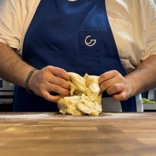 Un uomo che indossa un grembiule blu con la lettera g sopra