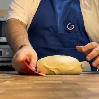 Una persona che indossa un grembiule blu con la lettera g sopra