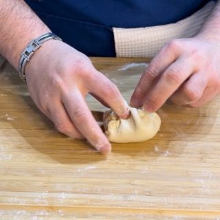 Una persona sta impastando la pasta su un tagliere di legno