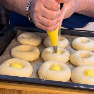 Una persona sta versando la glassa gialla in un mucchio di ciambelle