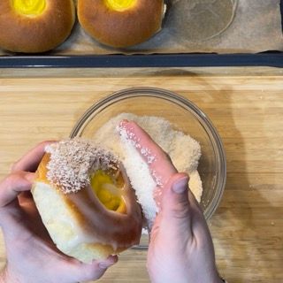 Una persona tiene in mano una ciambella ricoperta di zucchero a velo