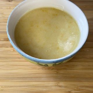 Una ciotola di zuppa è appoggiata su un tavolo di legno.