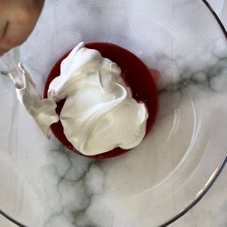 Una persona sta versando la panna montata in una ciotola rossa.