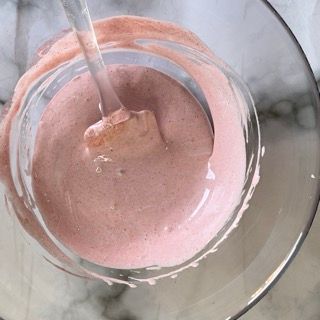 Una ciotola di liquido rosa con un cucchiaio dentro