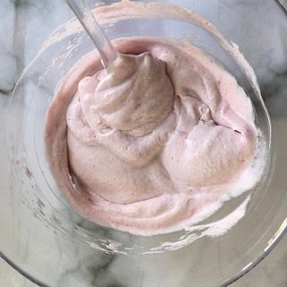 Una ciotola di gelato rosa con un cucchiaino dentro.