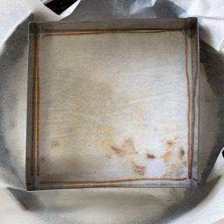Una padella quadrata è appoggiata su un cerchio di carta oleata