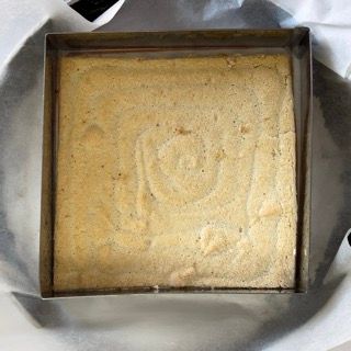 Una padella quadrata piena di una sostanza gialla è appoggiata su un piatto.