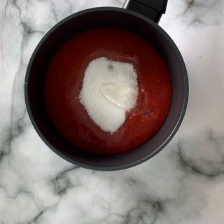 Una pentola di salsa di pomodoro con lo zucchero al centro