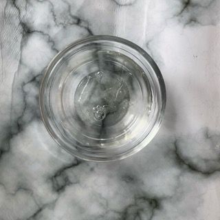 Un bicchiere d'acqua è appoggiato su un tavolo di marmo.