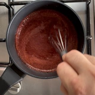 Una persona sta mescolando una pentola di liquido rosso su un fornello.