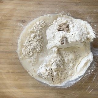 Una ciotola di farina e liquido su un tavolo di legno.