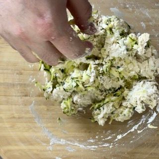 Una persona sta mescolando il cibo in una ciotola su un tavolo di legno