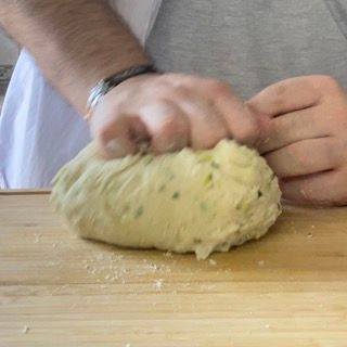 Una persona sta impastando l'impasto su un tagliere di legno.