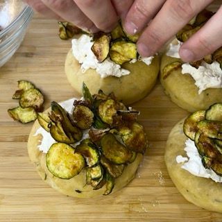 Una persona sta mettendo le verdure su un panino su un tagliere