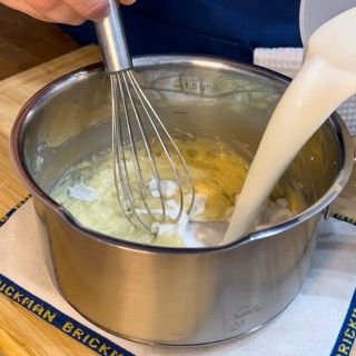 Latte freddo versato nel pentolino con il roux caldo, lontano dal fuoco.
