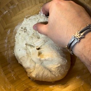 Una persona che indossa un braccialetto sta mescolando l'impasto in una ciotola