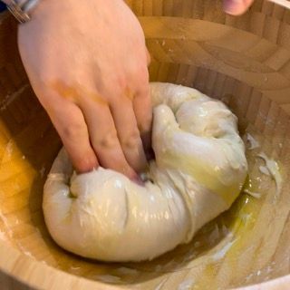 Una persona sta impastando una palla di pasta in una ciotola di legno