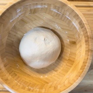 Una palla di pasta è in una ciotola di legno.