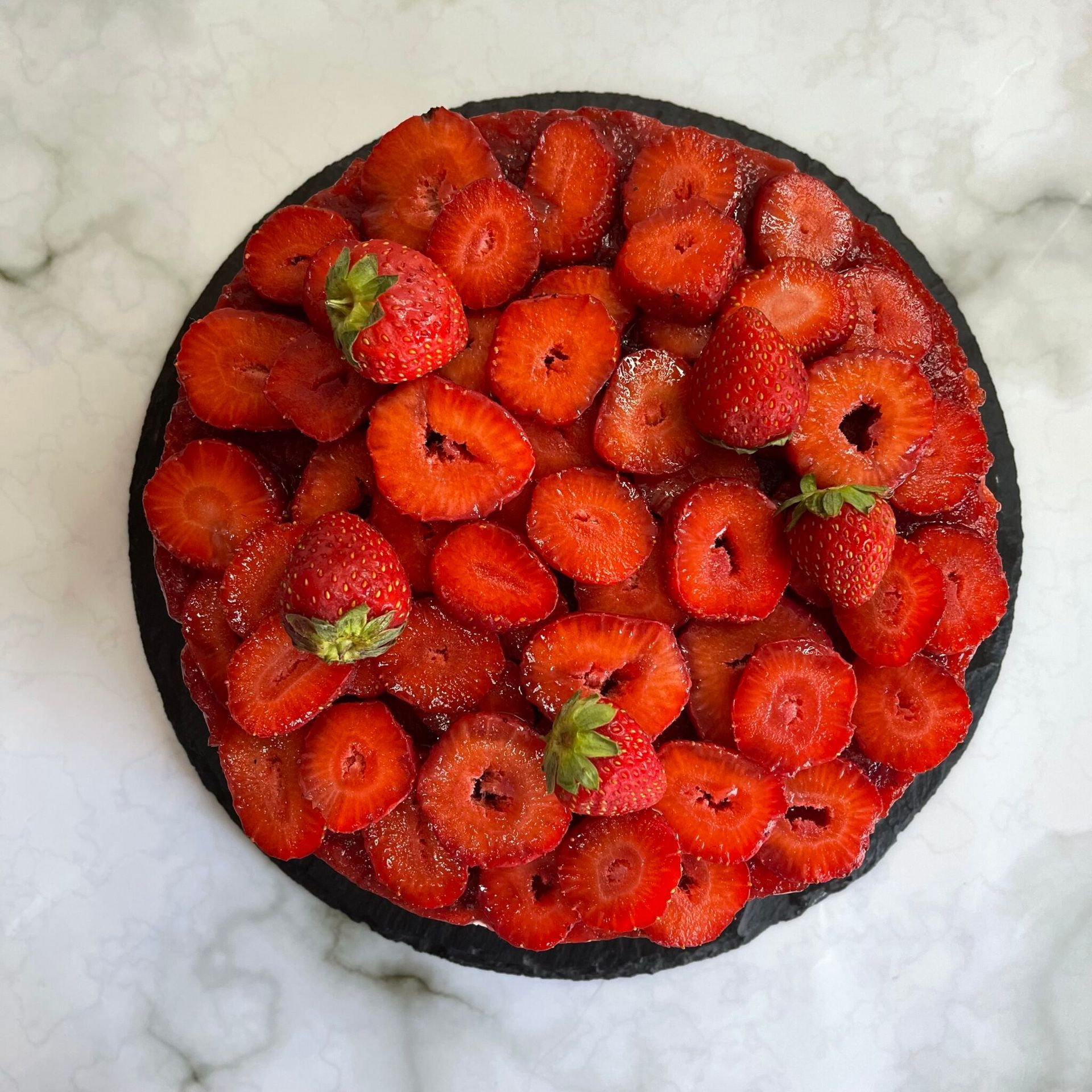 Una torta alle fragole è appoggiata su un tavolo di marmo.