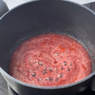 Una pentola piena di liquido rosso sta cuocendo sul fornello.