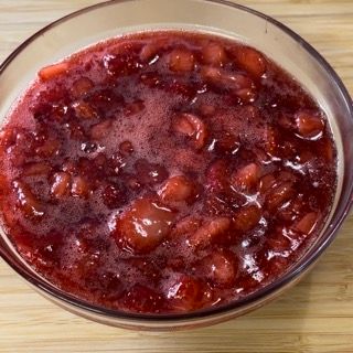 Una ciotola di salsa di mirtilli rossi è appoggiata su un tavolo di legno.