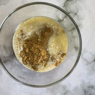 Una ciotola di vetro piena di un liquido giallo e polvere marrone