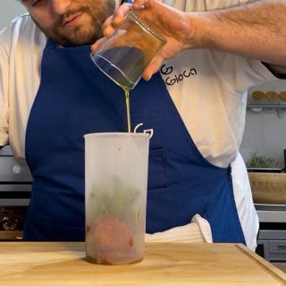 Un uomo con un grembiule blu che versa del liquido in una tazza