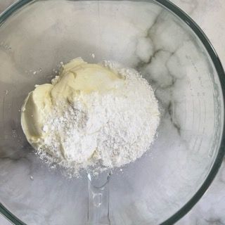 Una ciotola di vetro piena di farina e burro su un tavolo.