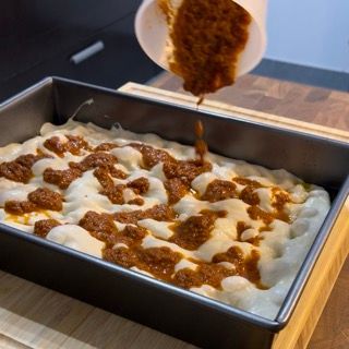 Una persona sta versando la salsa in una padella di cibo