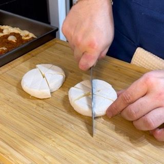 Una persona sta tagliando il pane su un tagliere di legno