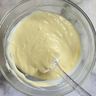 Una ciotola di salsa gialla con un cucchiaio dentro.