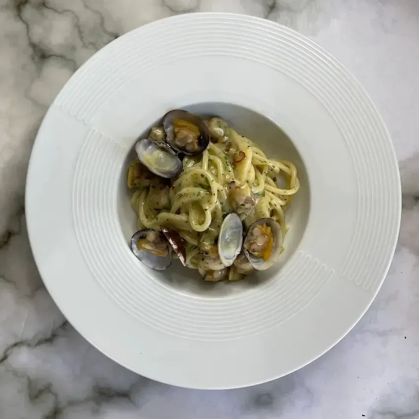 Piatto di spaghetti alle vongole cremosi, mantecati con prezzemolo fresco e vongole veraci.