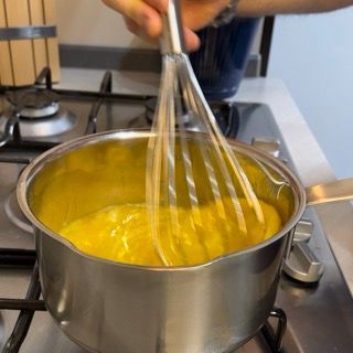 Frusta che mescola le uova sul fuoco