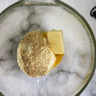 Un frullatore pieno di noci e burro su un tavolo.