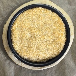 Una ciotola di riso è posta sopra un impasto per pizza