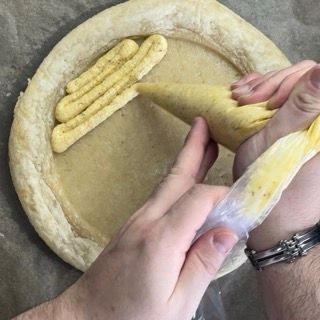 Una persona sta riempiendo una pizza con salsa gialla