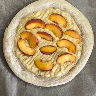 Una pizza con sopra delle pesche tagliate a fette