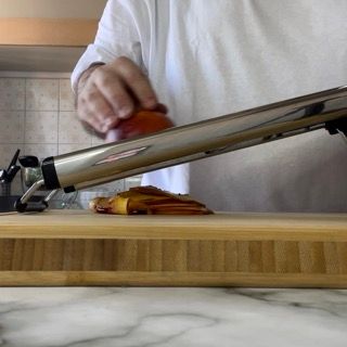 Un uomo sta tagliando una cipolla su un tagliere di legno