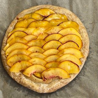 Una pizza con sopra delle pesche tagliate a fette