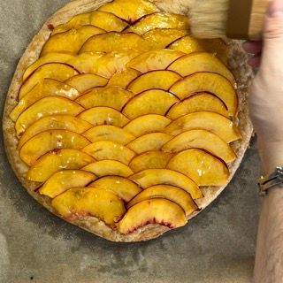 Una persona sta spennellando una torta di pesche con un pennello