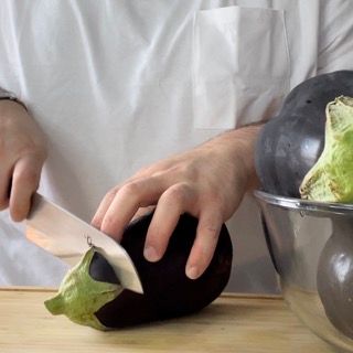 Una persona sta tagliando una melanzana su un tagliere