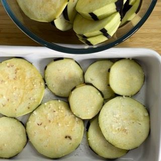 Una ciotola di melanzane a fette accanto a una padella di melanzane