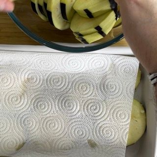 Una persona tiene in mano una ciotola di patate a fette su un tovagliolo di carta