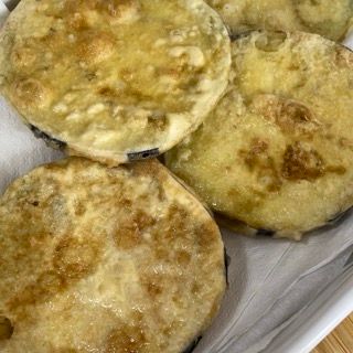 Un primo piano di melanzane fritte su un piatto su un tavolo.