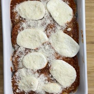 Una teglia bianca piena di polpette e formaggio