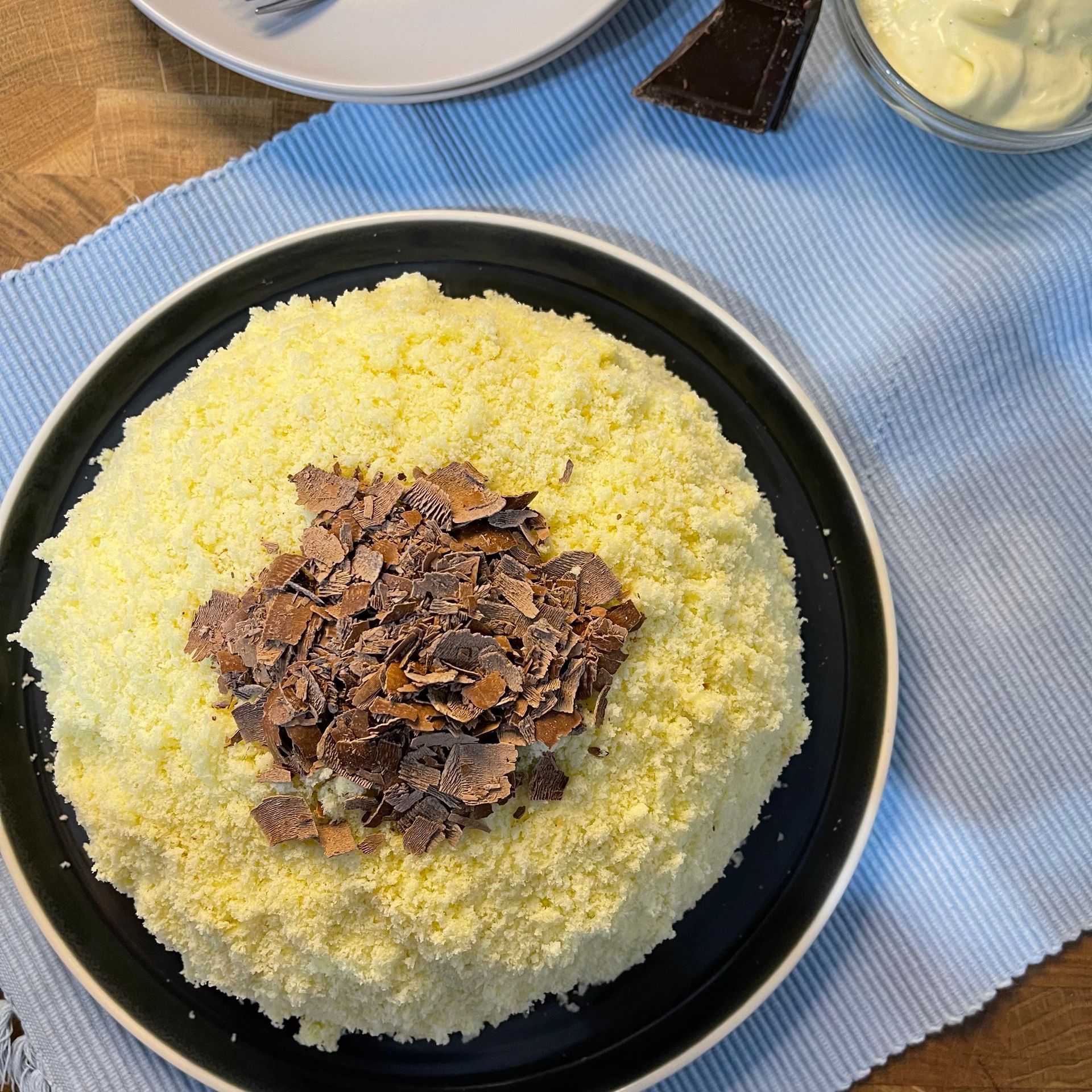 Una torta gialla con scaglie di cioccolato sopra su un piatto nero