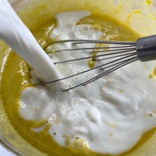 Latte caldo versato a filo sul composto di tuorli