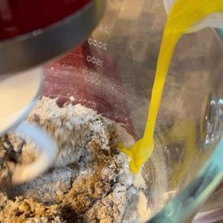 Una persona sta versando del liquido giallo in una ciotola di farina.