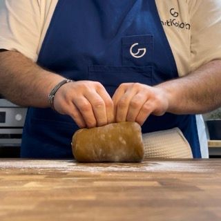 Un uomo che indossa un grembiule blu con la lettera g sopra